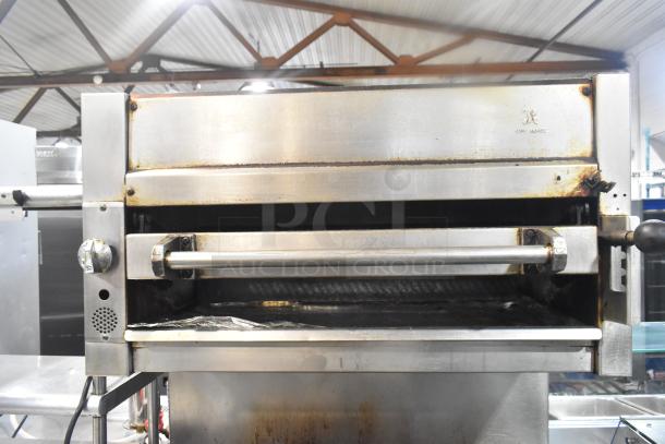 Commercial 6-burner gas range with salamander cheese melter and oven. Features visible wear; brand is Jade Range.