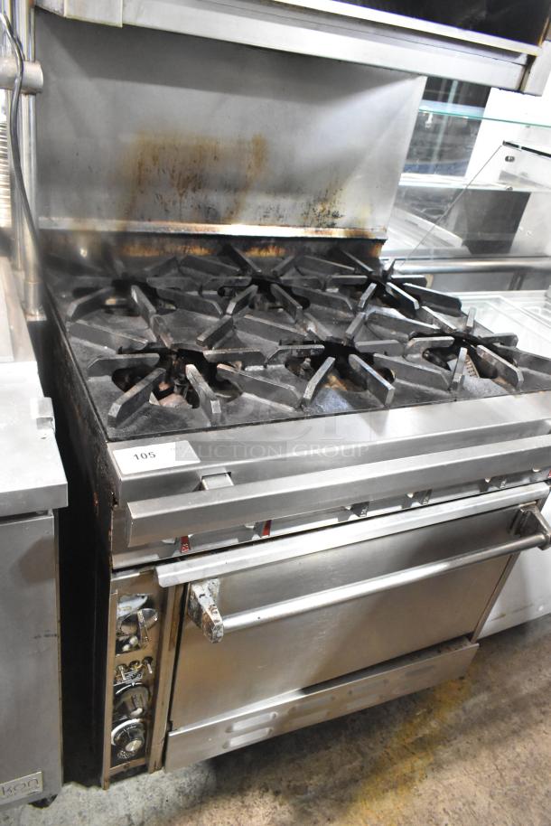 Commercial gas-powered range with 6 burners, salamander cheese melter, and oven. Stainless steel, industrial condition.