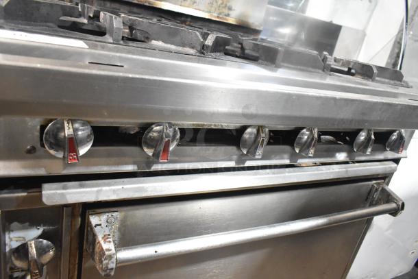 Commercial gas-powered 6 burner range with salamander cheese melter and oven. Features stainless steel knobs. Good condition.