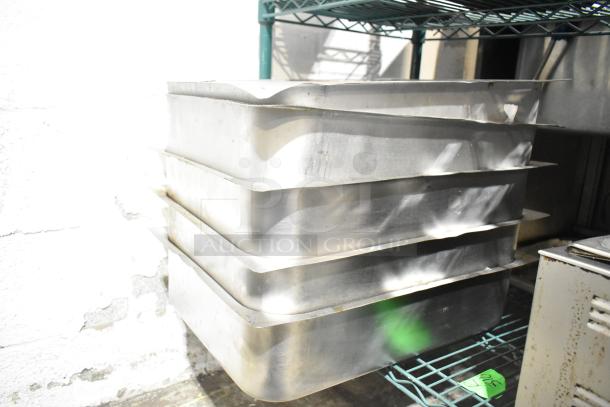 Stack of 5 stainless steel steam pans, rectangular shape, fair condition, placed on a shelf.