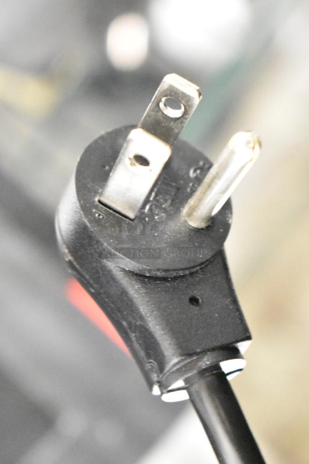 Close-up of a black electrical plug with visible prongs, potentially for powering APC uninterruptible power supplies.