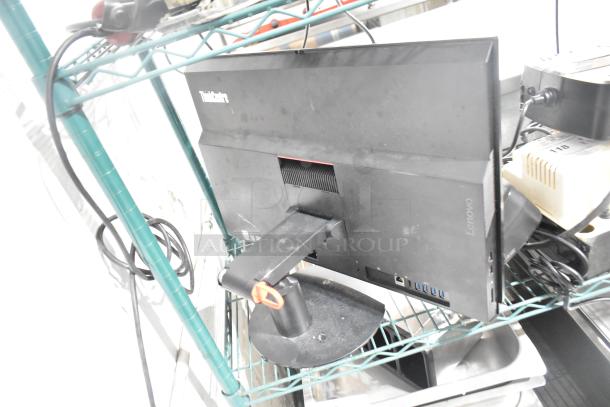 Lenovo ThinkCentre monitor on a shelf with visible ports; condition appears used. Two APC uninterruptible power supplies nearby.