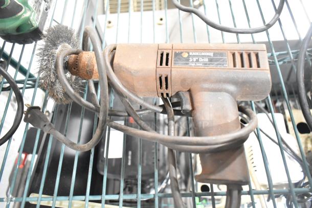 Assorted tools including Black & Decker 3/8" drill with cord, visible wear, single speed, in storage rack.
