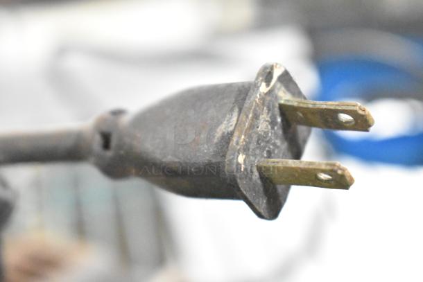 Close-up of a used electrical plug, part of a lot including tools like a Craftsman sander, Hitachi driver, and Skilsaw.