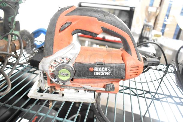 Black and Decker saw with adjustable dial, orange and black handle, displayed on metal shelf; visible wear.