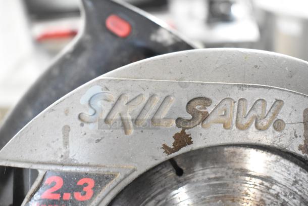 Close-up of a Skilsaw with visible wear, highlighting the logo and a "2.3" marking. Part of a mixed tool lot.