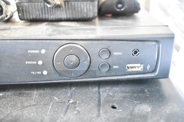 Front panel of Alarmcom unit with power and status indicators, menu and escape buttons, and USB port; dusty condition.