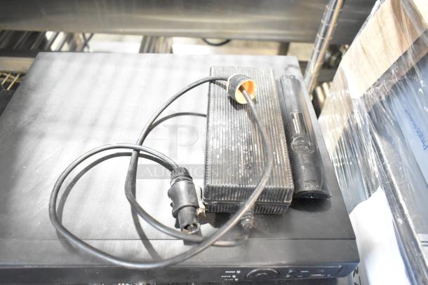 2 items: Alarmcom unit and cash drawer. Alarmcom unit shows power cable and condition appears fair. Auction lot doubles bid value.