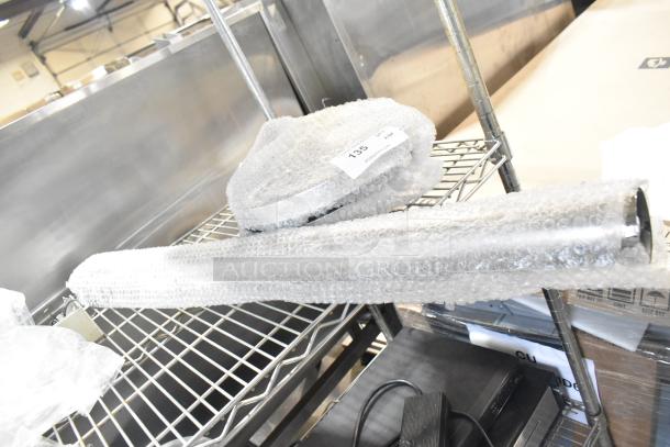 BRAND NEW SCRATCH AND DENT! Lancaster stanchion wrapped in bubble wrap, tagged with item number 135 on metal shelf.