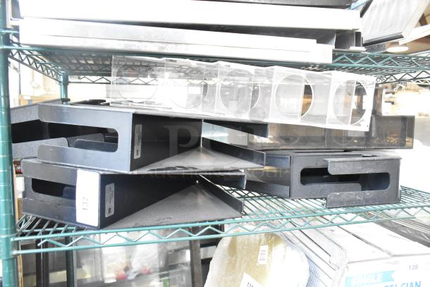 Seven various items including a lid dispenser on a metal shelf. Black stackable trays marked "137" visible. Items in used condition.