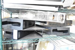 Seven various items including a lid dispenser on a metal shelf. Black stackable trays marked "137" visible. Items in used condition.