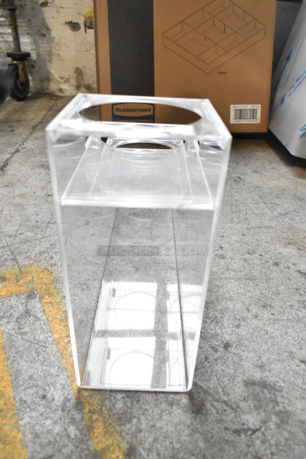 Clear plastic lid dispenser, Rubbermaid branded box in background, good condition, industrial setting.