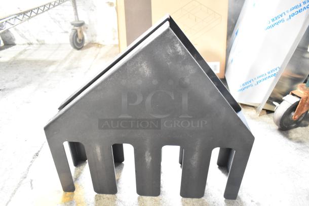 Black plastic lid dispenser, rectangular shape, with multiple slots, used condition, in a warehouse setting.