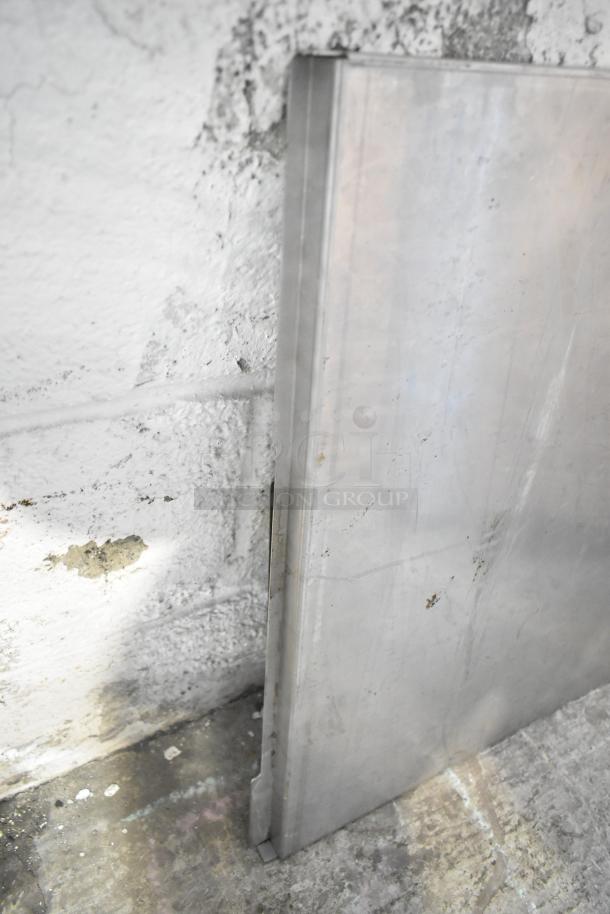 Metal panel leaning against a textured wall; part of a mixed lot with metal pieces and a blue poly rack. Slight wear visible.