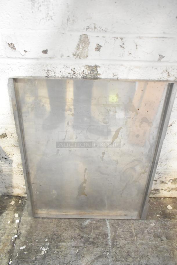 Metal sheet leaning against a white wall, showing some wear and rust stains, part of a mixed tier lot.