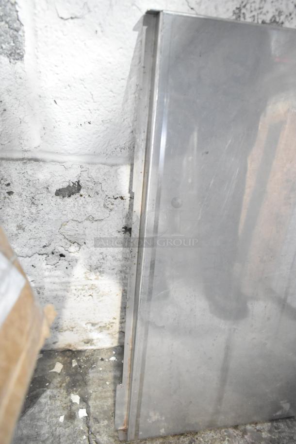 Metal sheet panel leaning against a textured wall, minimal rust visible on edges. Part of tier lot with various items.