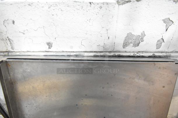 A collection of metal pieces and a blue poly rack against a cracked white wall, showcasing varying conditions.