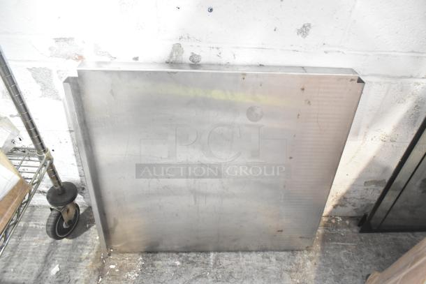 Assorted metal pieces leaning against a wall, part of a mixed auction lot that includes a blue poly rack. Visible wear and scratches.