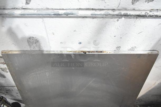Alt text: Metal sheet leaning against a textured white wall, part of an auction lot including metal pieces and a blue poly rack.