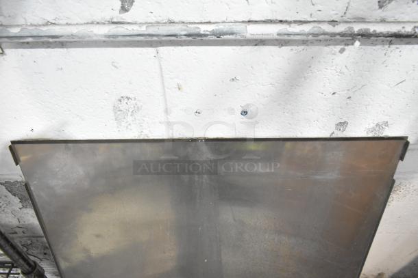 Assorted metal sheet, part of an auction lot, leaning against a wall with visible wear and rustic texture.