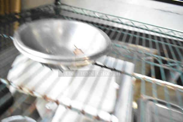 Blurry image of a metal bowl on a wire shelf. Part of a lot of 25 various metal bowls for auction.