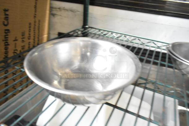 25 metal bowls in various sizes on a wire rack, shiny finish, appear in good condition. Auction includes entire set.