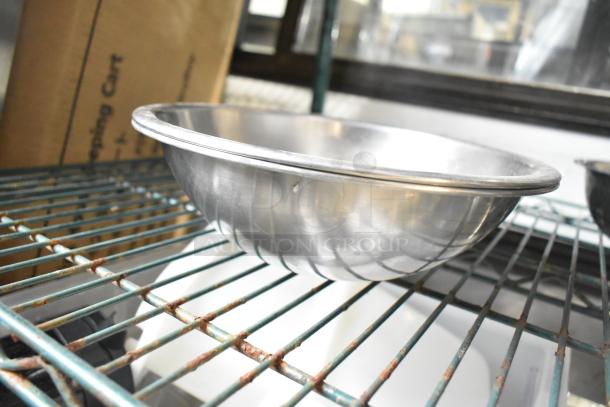 Silver metal bowl on a wire rack, part of a lot of 25 various metal bowls. Gently used with visible mild wear.