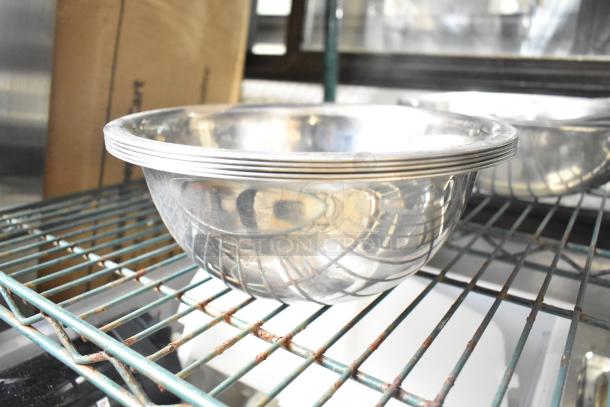 Set of 25 metal bowls, shiny surface with subtle pattern, stacked on a wire shelf, ideal for kitchenware.