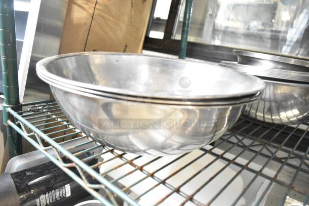25 various metal bowls stacked on a wire shelf, shiny and in good condition, ideal for kitchen use or resale.