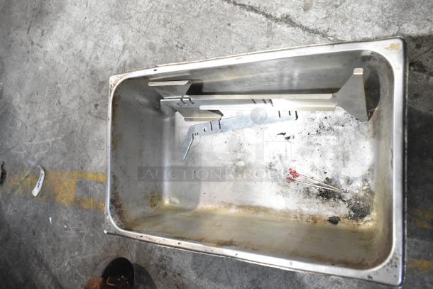 Metal bin showing signs of wear with assorted metal brackets and small debris inside, part of a mixed-item auction lot.