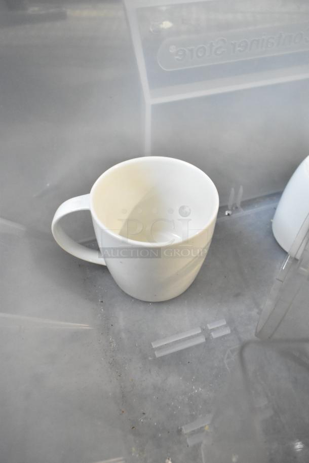 White ceramic mug in used condition, placed inside a transparent bin marked "Container Store."