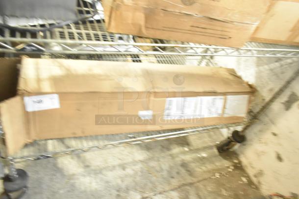 Cardboard box containing a scratch and dent black anti-fatigue floor mat, resting on a metal shelf. Package shows wear.