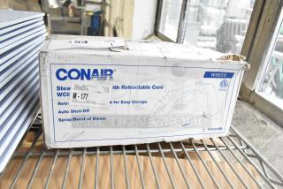 Conair Steam Iron, Model WCH306R, with retractable cord in original packaging. Features auto shut-off, spray/burst of steam. Box slightly worn.