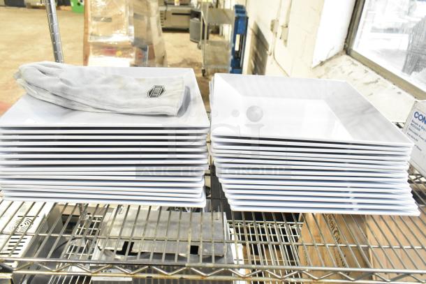Stack of white square plates and a pair of Ironcat gloves on a metal rack. Plates appear in good condition.