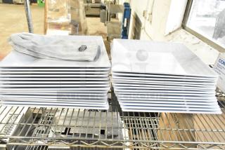 Stack of white square plates and a pair of Ironcat gloves on a metal rack. Plates appear in good condition.
