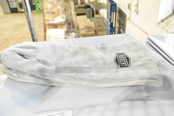 A pair of Ironcat gloves displayed on a table; fabric is light-colored with visible dirt marks; Ironcat logo on gloves.