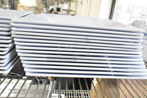 Stack of white plates on a metal shelf, part of a 31-item auction lot including Ironcat gloves. Plates appear new and unused.