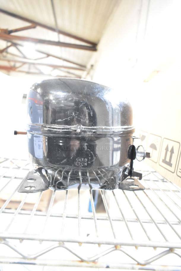 Cubigel NUY100NR compressor motor, black finish, 115-127 Volts, 1 Phase, visible surface wear, metal base mount.