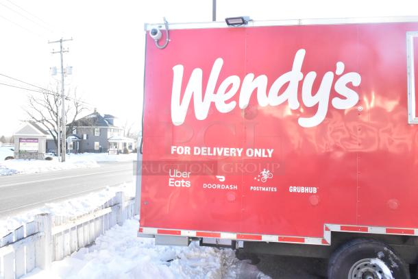 2021 Titanium Cargo 8.5' x 28' mobile kitchen trailer, red with Wendy's branding, and delivery service logos. Snowy roadside setting.