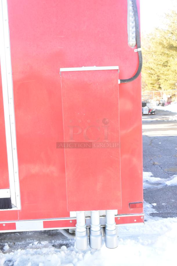 Red rear panel of a 2021 Titanium Cargo mobile kitchen trailer, showcasing electrical and plumbing connections.