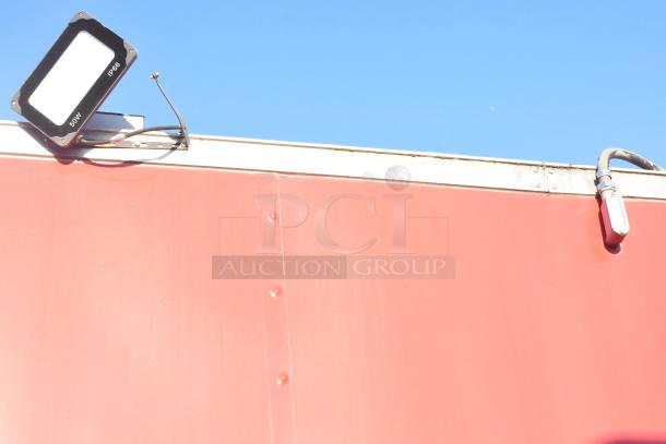 Red exterior of 2021 Titanium Cargo 8.5' x 28' mobile kitchen trailer with mounted floodlight.