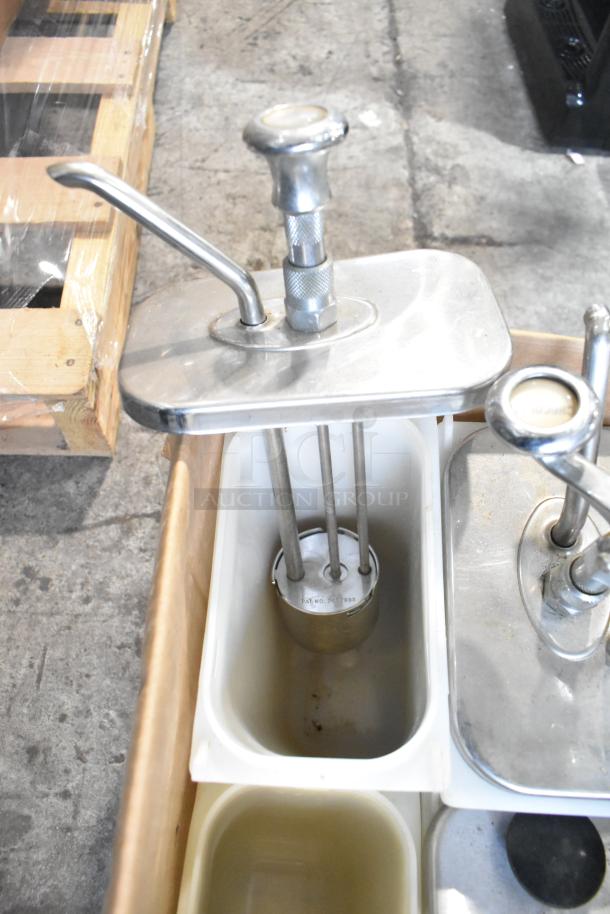Stainless steel topping dispensers with pump handles and white containers in good condition; patent markings visible.