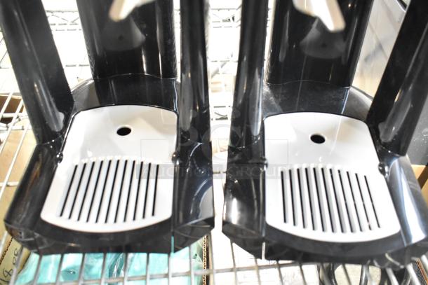 Two black and white beverage dispenser bases with grated trays for collecting drips, in good condition.
