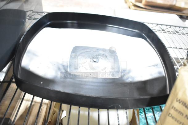 Gray Slim Jim Trash Can Lid, model 34202423, shown on a shelf. Includes Winco steam pan lids. Condition unknown.