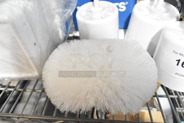 Four cleaning brushes on a shelf, including three toilet brushes and one general brush, in new condition.