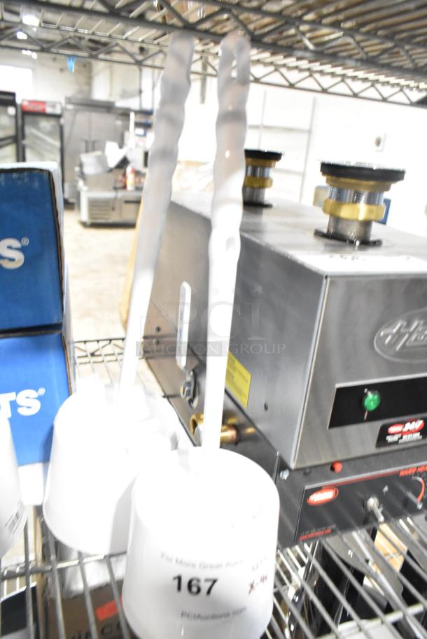 Four white toilet brushes on a shelf. Two have labels marked "167," indicating auction lot number.