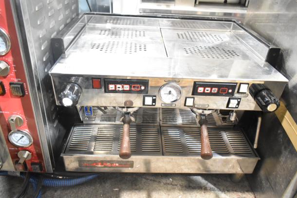 La Marzocco commercial 2-group espresso machine with portafilters and steam wands. Features control panel and pressure gauge.