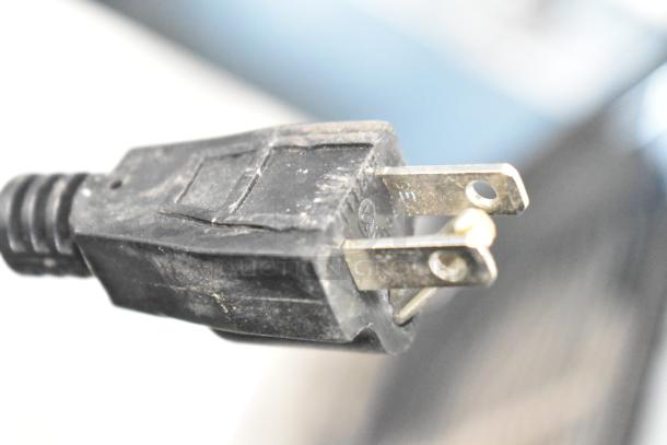 Close-up of a 115V power plug for the 2023 Carnival King 382SMM1 granita machine, showing prongs and slight wear.