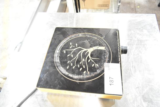 Countertop single burner induction range with a cooktop crack, decorative design, and control knob. Auction tag marked as 187.