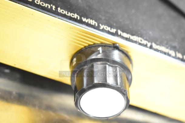 Countertop single burner induction range with control knob. Visible text warning and small crack on cooktop.